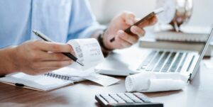 man holding pen using calculator