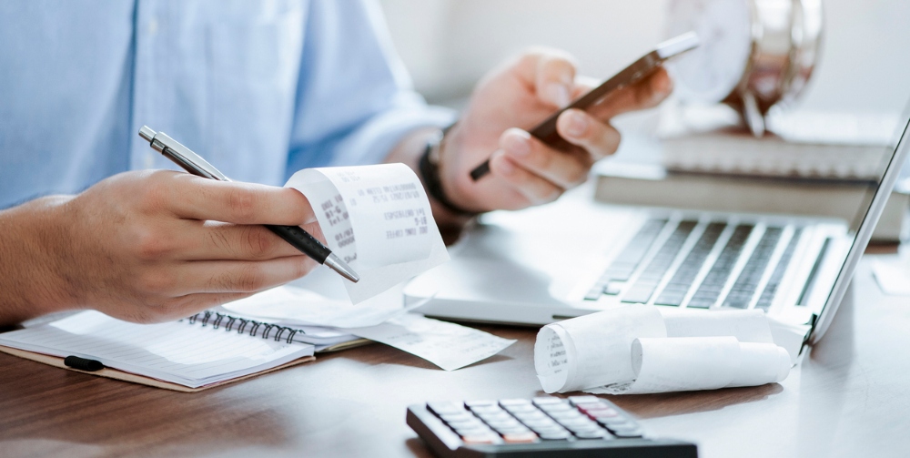 man holding pen using calculator