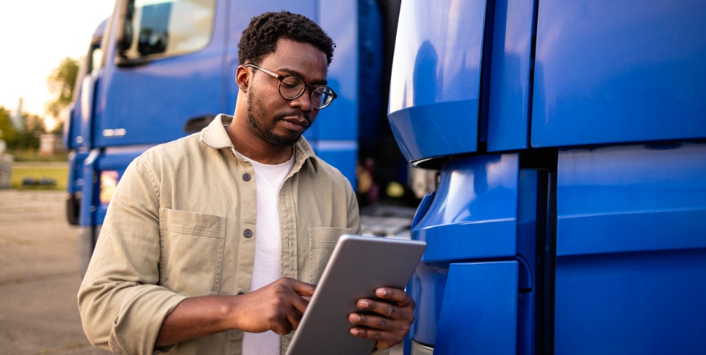 man looking at clipboard in front of fleet of trucks