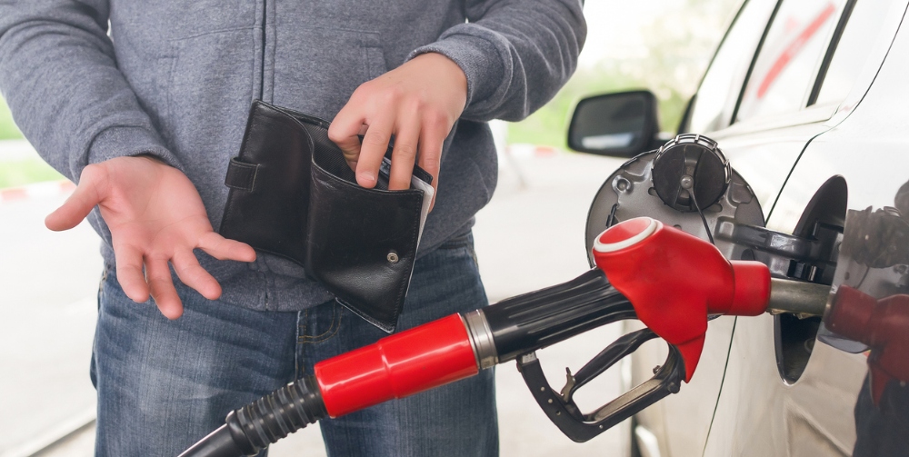 Driver holds wallet against the background of a fuel nozzle